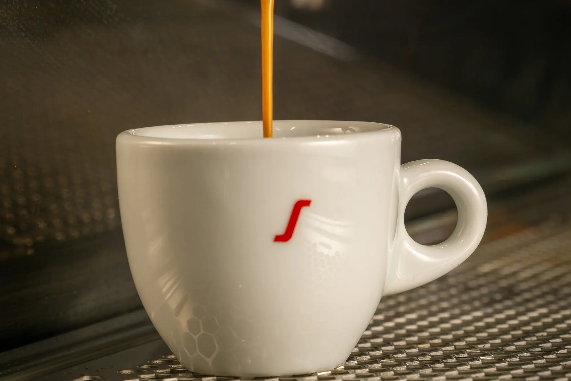 Café cayendo de la máquina a la taza